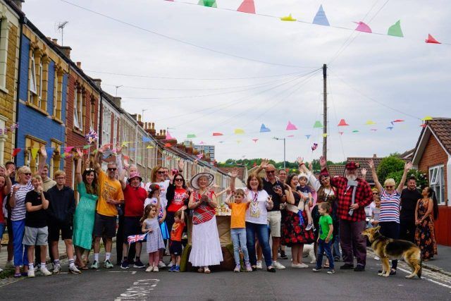 Group standing across street smiling, with colourful bunting